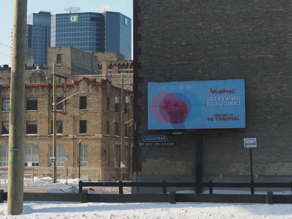 a billboard for Universal Language against a brick wall as viewed in a mirrored window