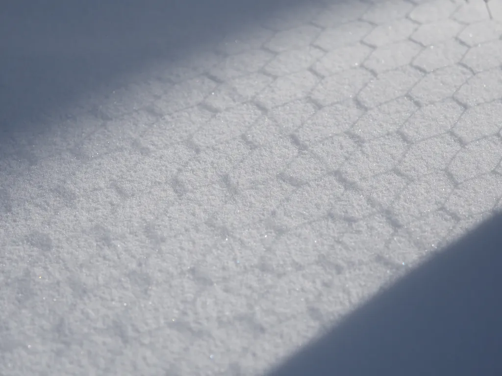 a fence's shadow on snow