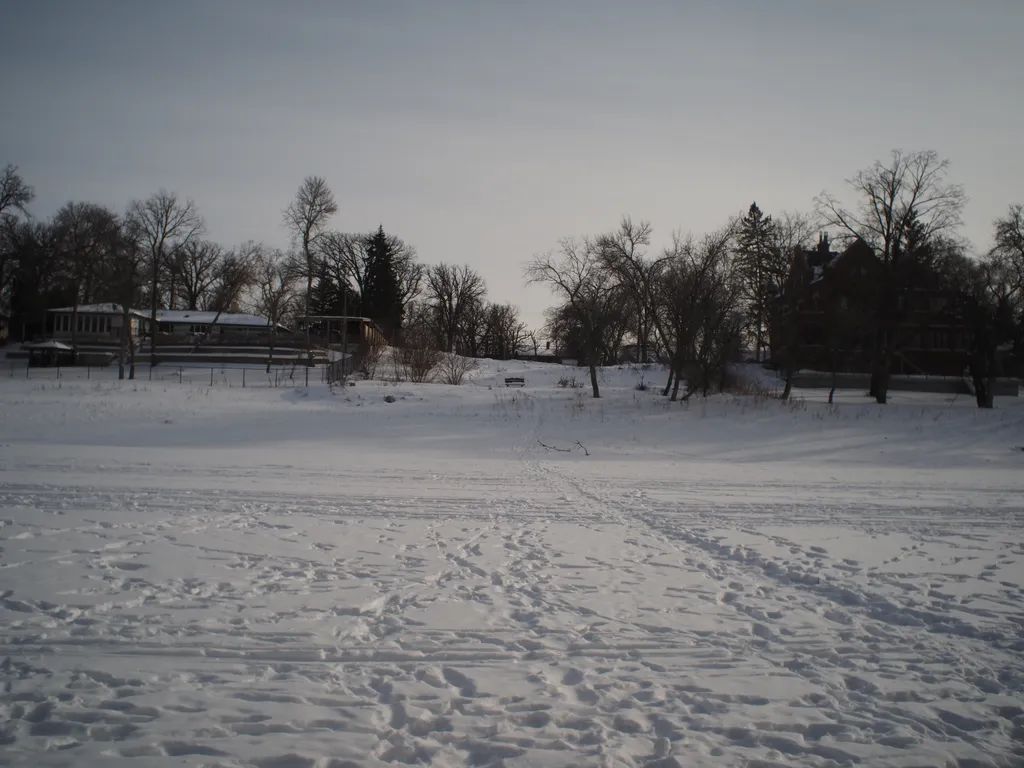 a snow-covered bench across a frozen river