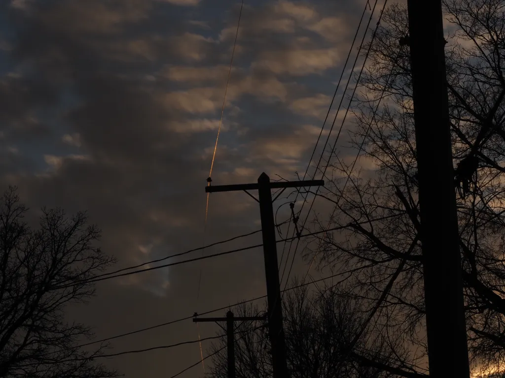 power lines lit from underneath by the setting sun