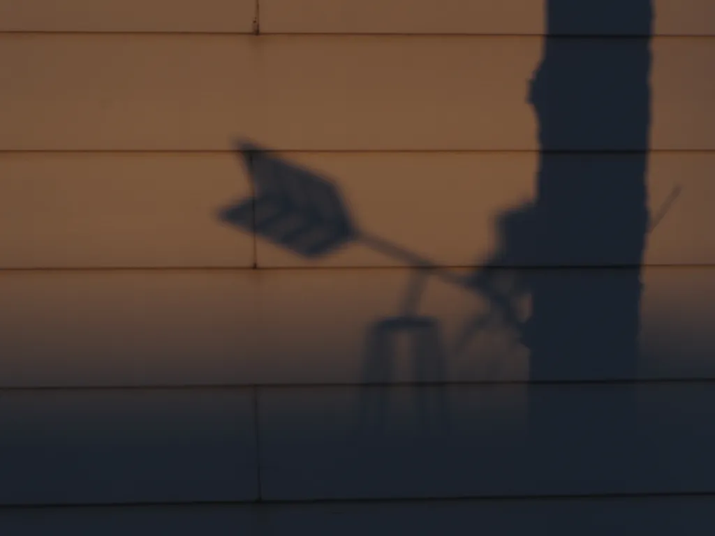 the shadow of a weather vane on a house