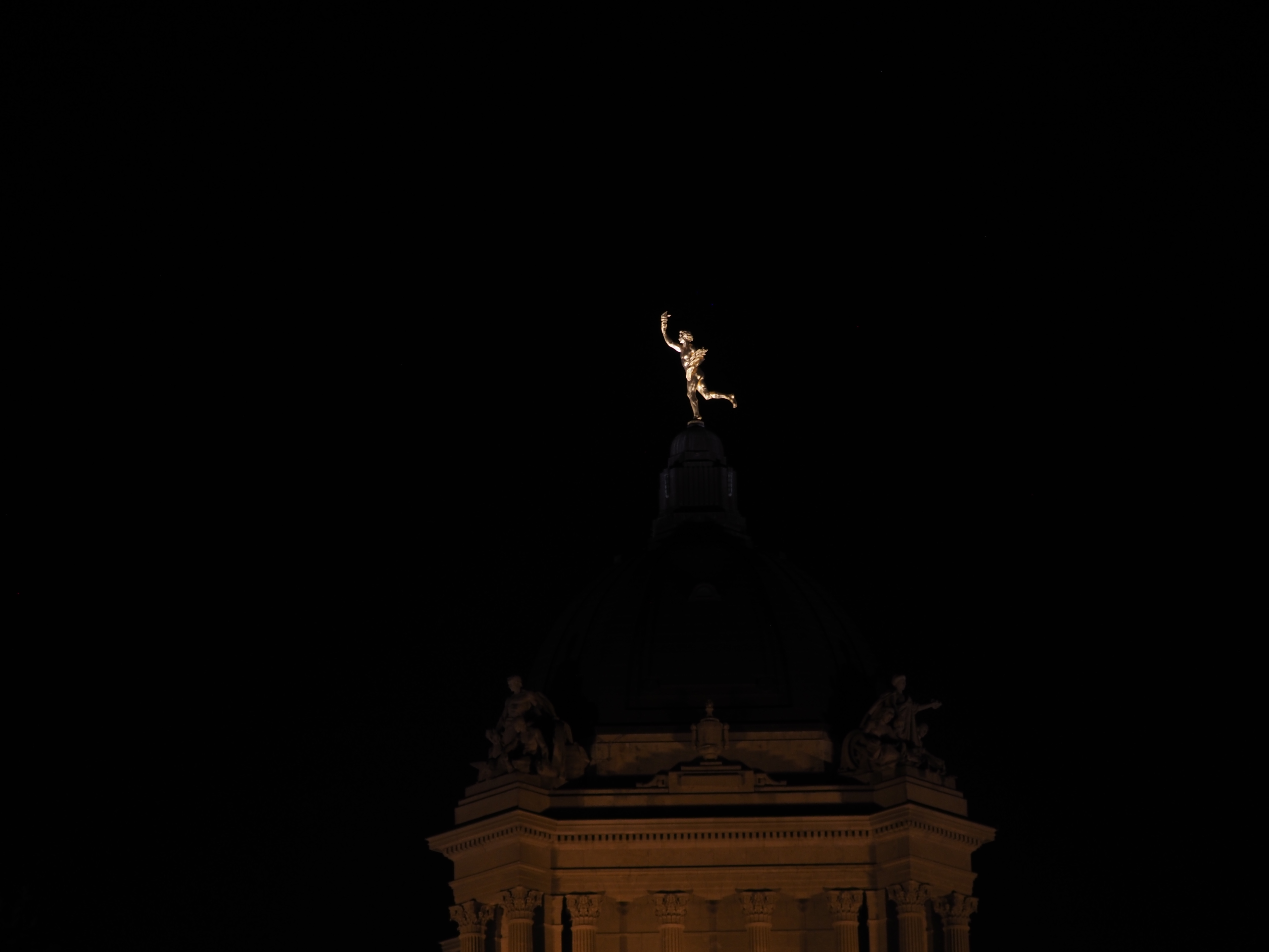 a golden statue lit up at night