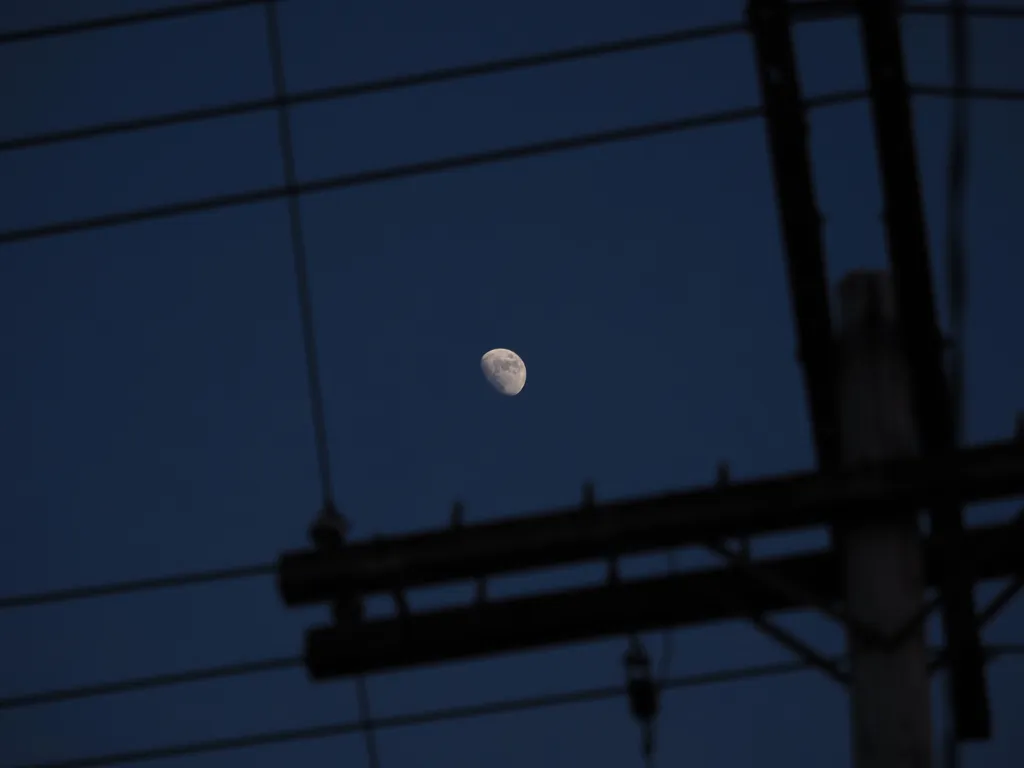 the moon surrounded by power lines