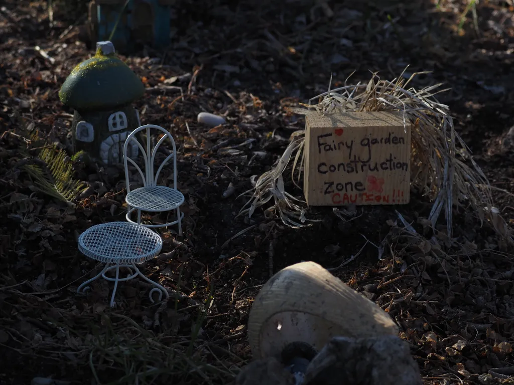 a miniature patio set by a sign labelling the area as a 'fairy garden construction zone'
