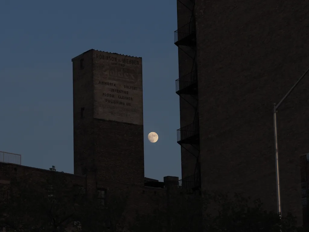 a large moon behind brick buildings
