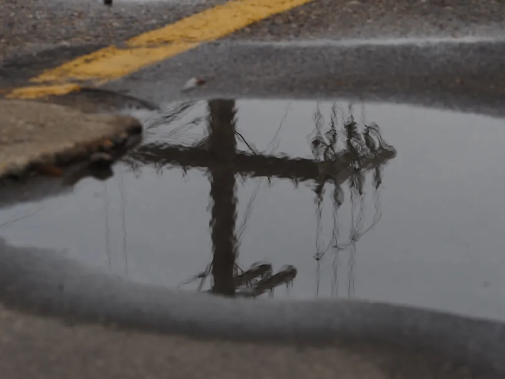 a telephone pole reflected in a puddle