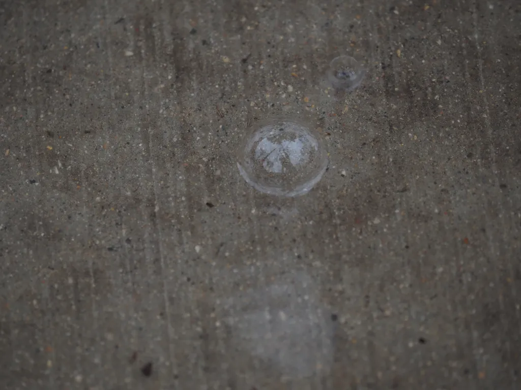 a large bubble in a small puddle on a sidewalk