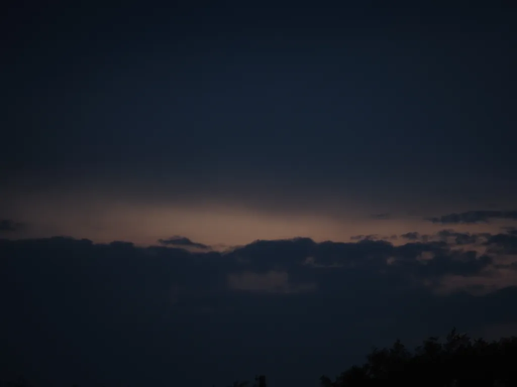 dark clouds with light behind them as the sun sets unseen