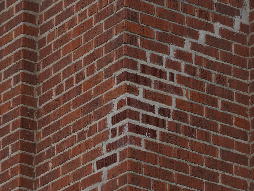 the corner of a brick building with a section that has obviously been repaired