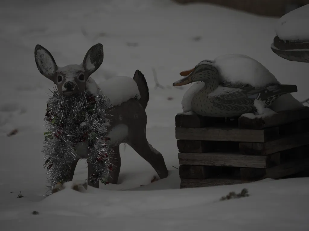 a plastic doe with tinsil around it next to 2 wooden ducks covered in snow