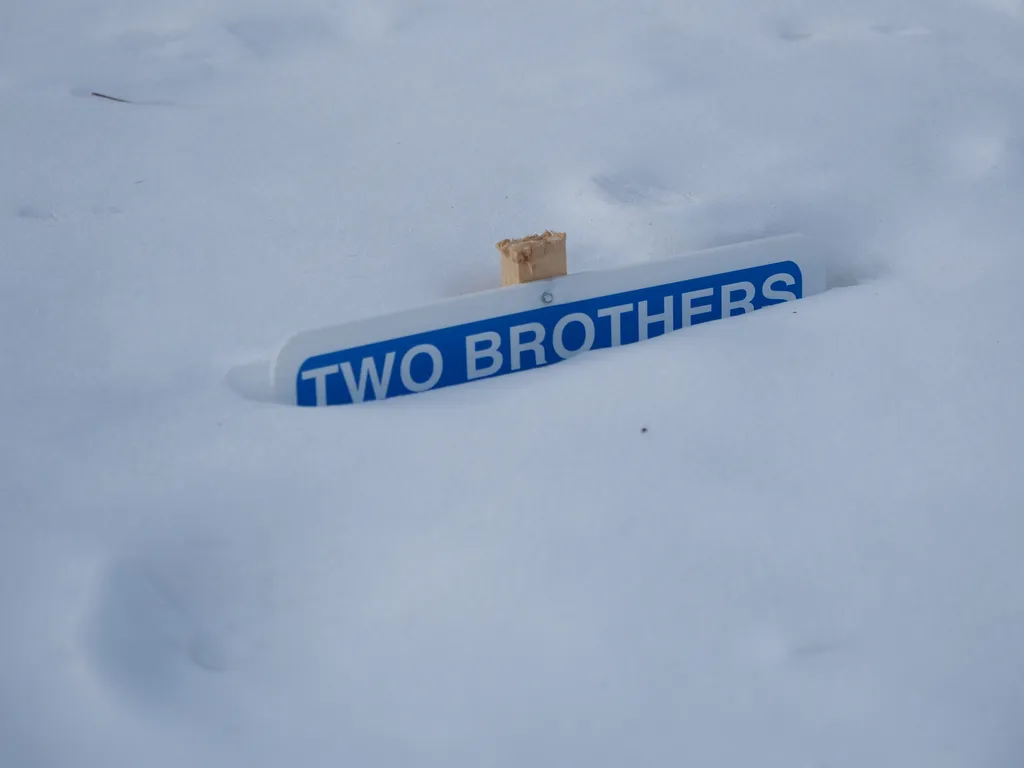 a yard sign almost completely burried in snow. All that is legible are the words 'two brothers' in all-caps