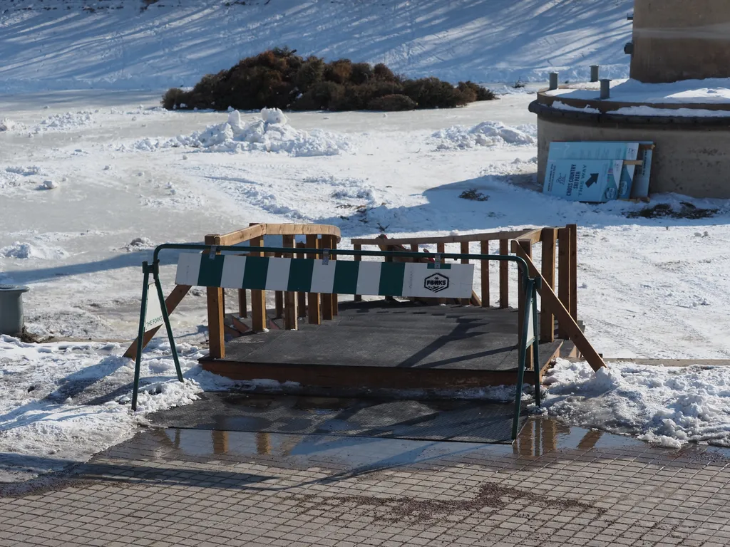 a barrier blocking an entry to a frozen river