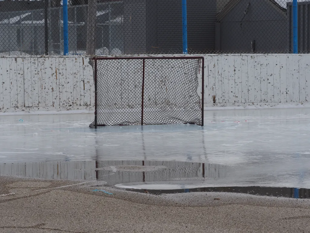 an empty net in a mostly-melted outdoor hockey rink