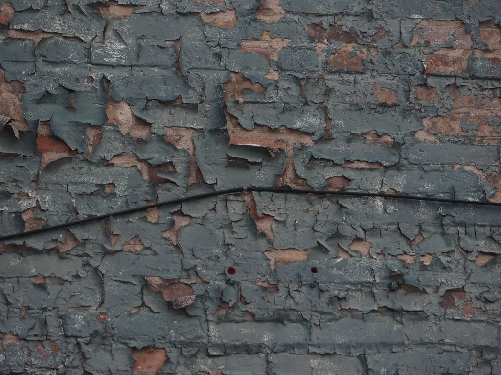 flaking green paint on a brick wall